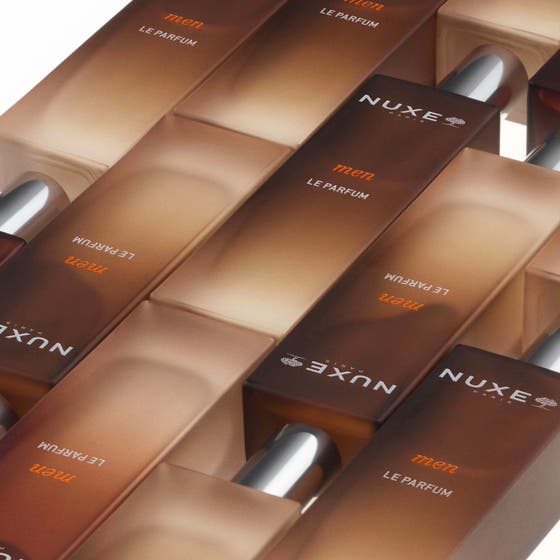 Nuxe Men Le Parfum 50ml herrparfym i brun gradientflaska som hålls mot en mans rygg i en lifestylebild