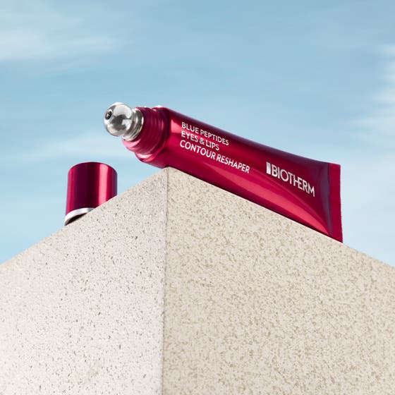 Biotherm Blue Peptides Eyes Lips 15 ml lyftande ögonvård i röd tub och burk med biotherm peptid mot en klarblå himmel.