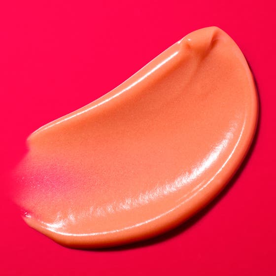 Nuxe Merveillance Lift Glow 50 ml anti-aging glow kräm i rödrosa tub placerad på en persikofärgad krämtextur.