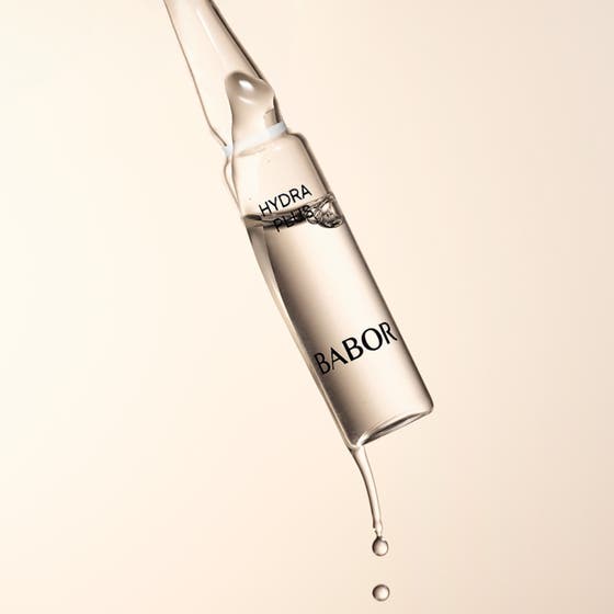 Babor Ampoule Hydra Plus 14 ml hyaluronsyra ampull ansiktsserum som droppar mot en beige bakgrund