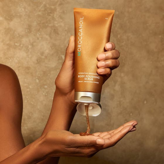 Moroccanoil Body Polishing Scrub återfuktande exfoliering i bronstub med kornig gel som trycks ut i en hand