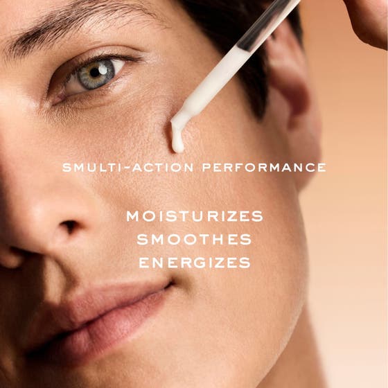 Nuxe Men Multi Action Serum 30 ml ger energi i en brun glasflaska framför trä och rinnande vit kräm.