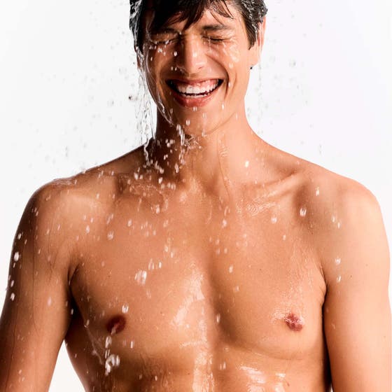 Nuxe Men Multi Shower Gel 200 ml rengörande duschtvål i brun tub som hålls mot en blöt rygg med vattenstänk