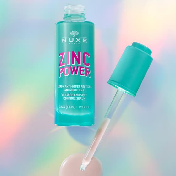 Nuxe Zinc Power Blemish And Spot Control Serum 30 ml motverkar blemmor i en turkos glasflaska med pipett och rosa text.