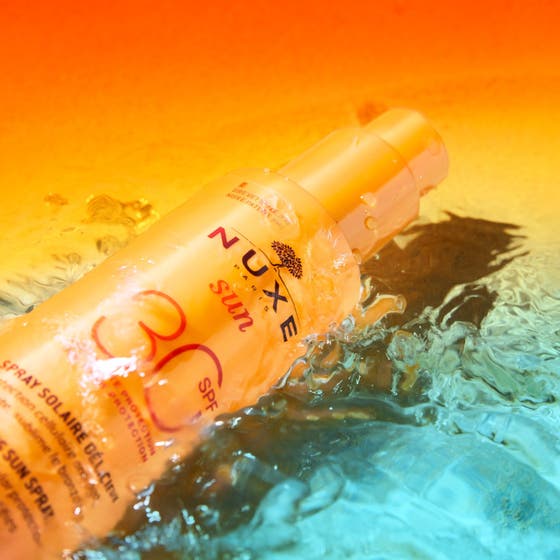 Nuxe Sun Spray SPF30 184 g anti-aging solskydd hydrering i orange flaska omgiven av svalkande vattenstänk