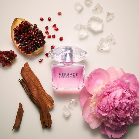 Versace Bright Crystal parfymset blommig parfym i rosa flaska omgiven av pion granatäpple och trä
