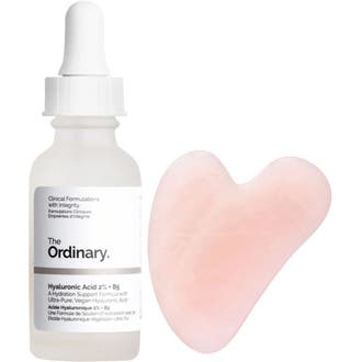 The Ordinary Hyaluronic Acid 2% + B5 återfuktande serum i frostad flaska bredvid en hjärtformad rosa gua sha.