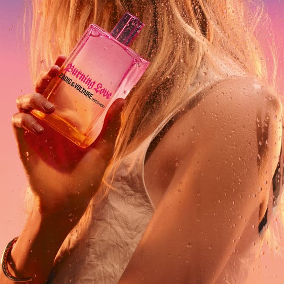Zadig & Voltaire This Is Her Burning Love 30 ml damparfym i en rosa glasflaska som hålls bakom en glasyta med vattendroppar
