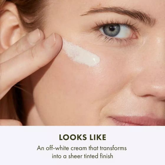 Origins GinZing SPF40 50 ml energigivande fuktkräm ansikte i tub som hålls av en kvinna mot orange bakgrund