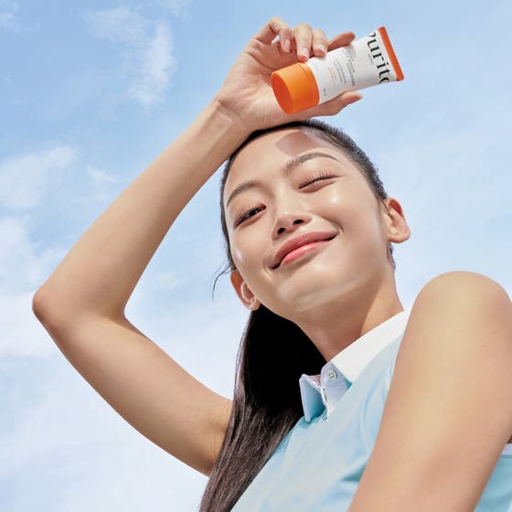 Purito Daily Soft Touch Sunscreen 60 ml daglig solkräm ansikte med ceramider i vita och orangea tuber bland vita bollar